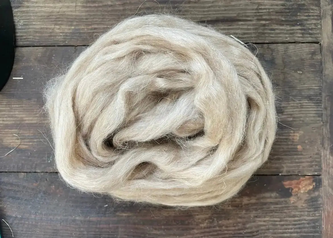 Ball of beige navajo churro wool on a wooden surface