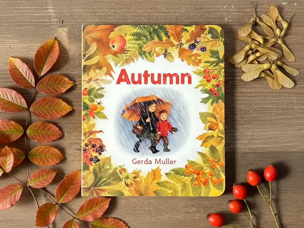 Book titled 'Autumn' by Gerda Muller on a wooden surface with autumn leaves and berries.