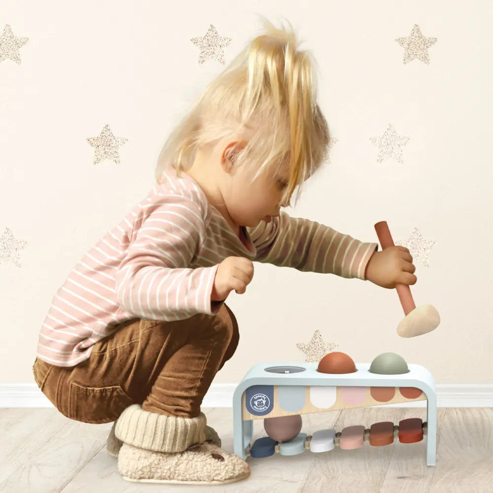 Toddler using wooden xylophone hammer bench toy with balls and mallet
