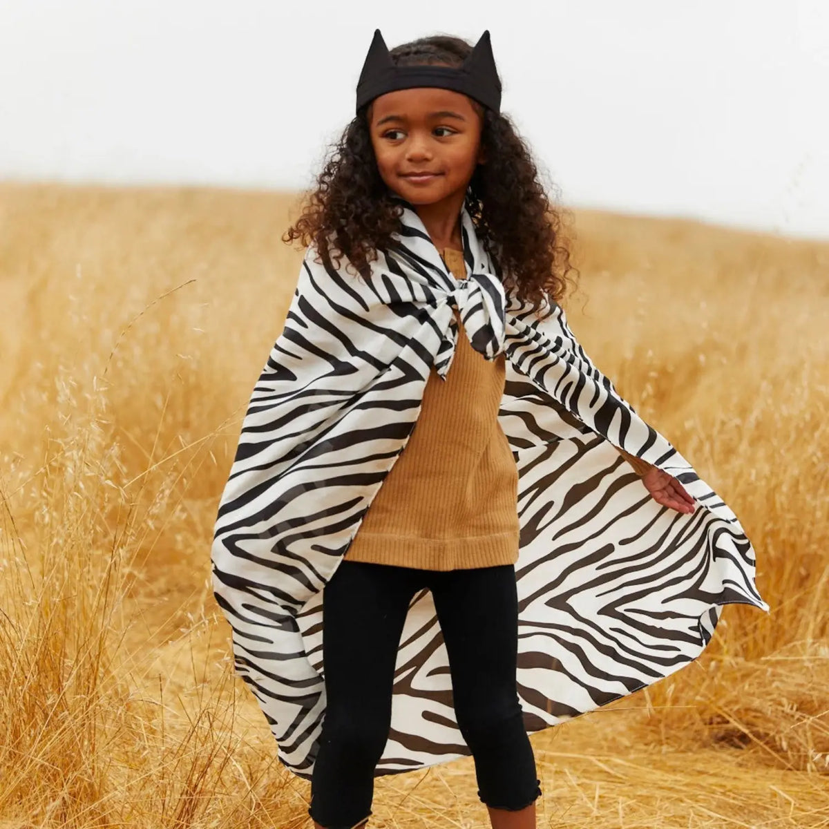 Child wearing a black and white Zebra Playsilk as a cape for imaginative animal dress-up play