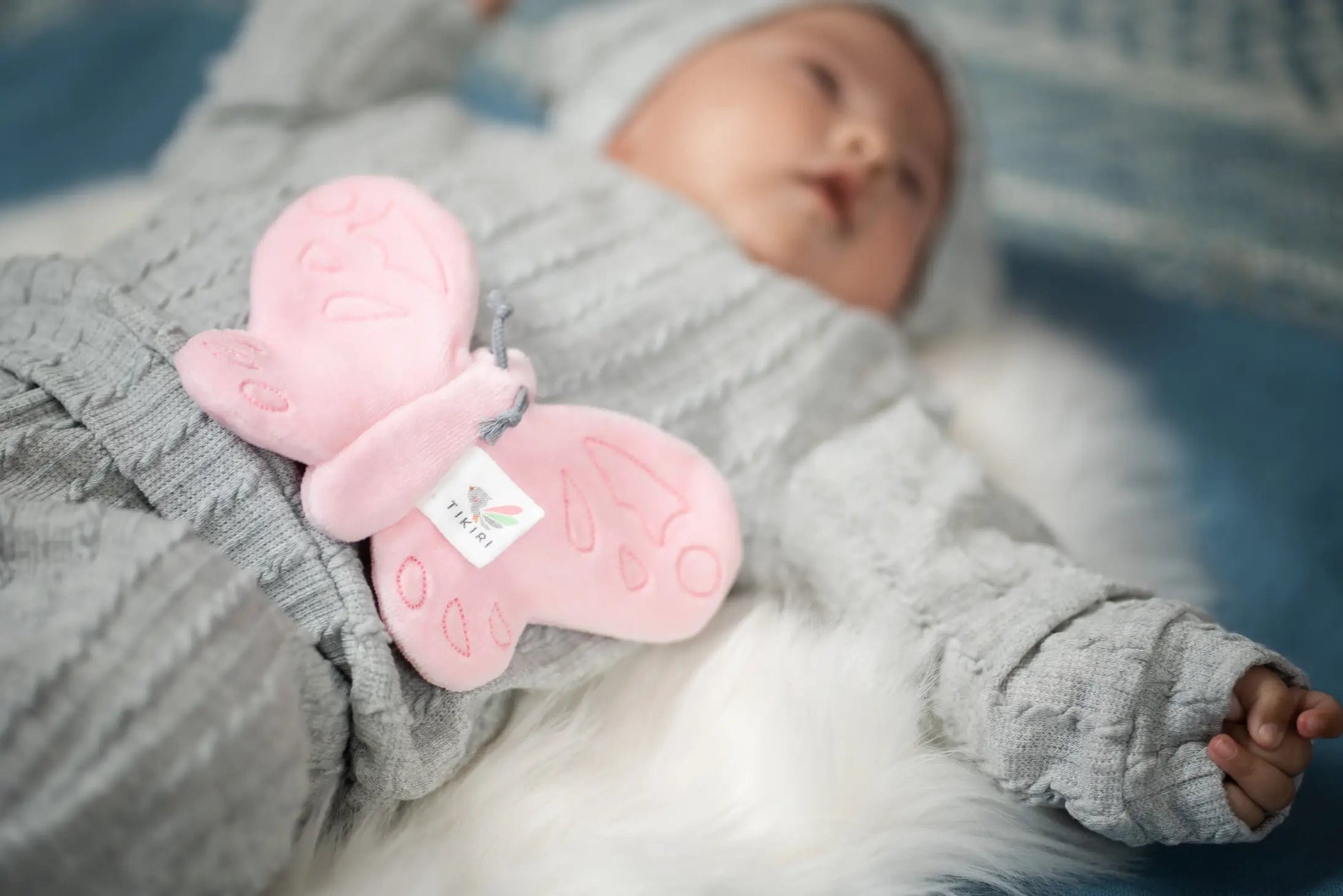 image of an infant laying on his or her back with a pink butterfly scrunchie toy 