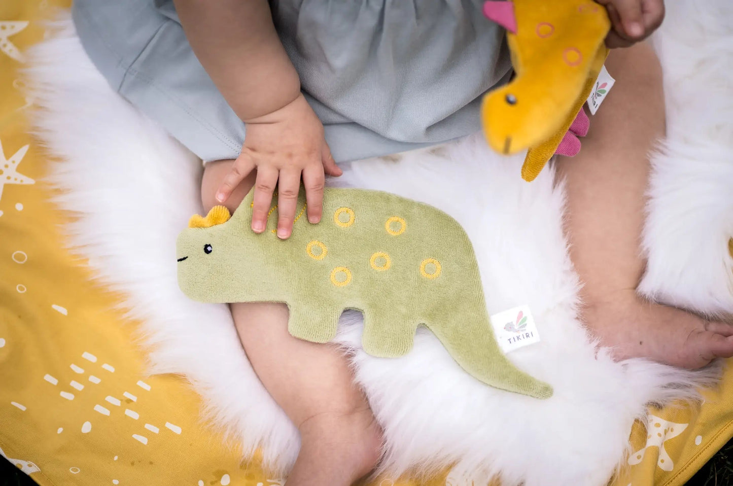 Baby holding a green crinkle triceratops sensory toy