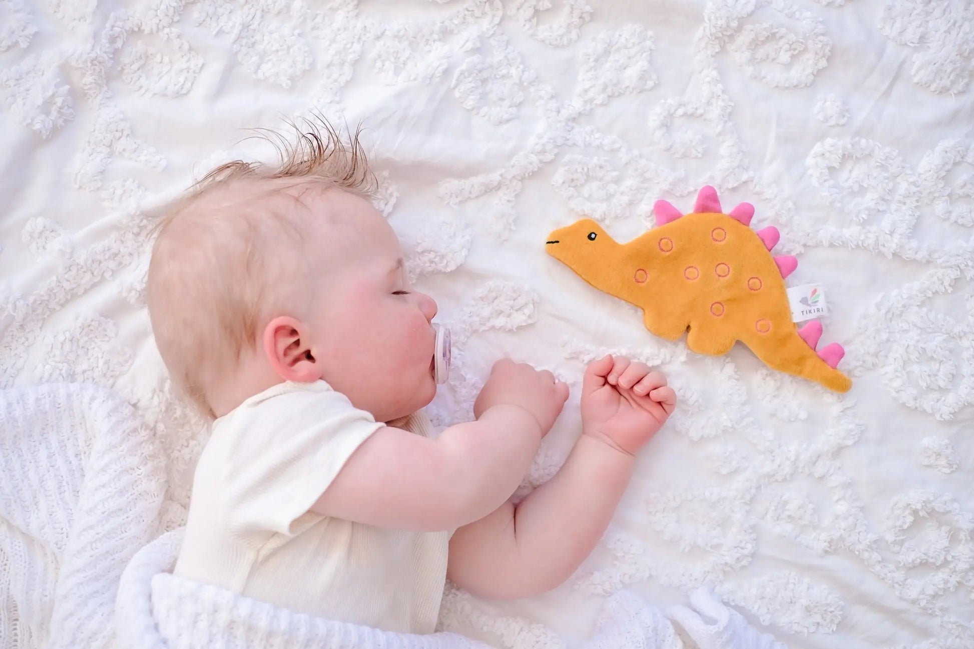 Baby next to Yellow and Pink Stegosaurus Crinkle Toy