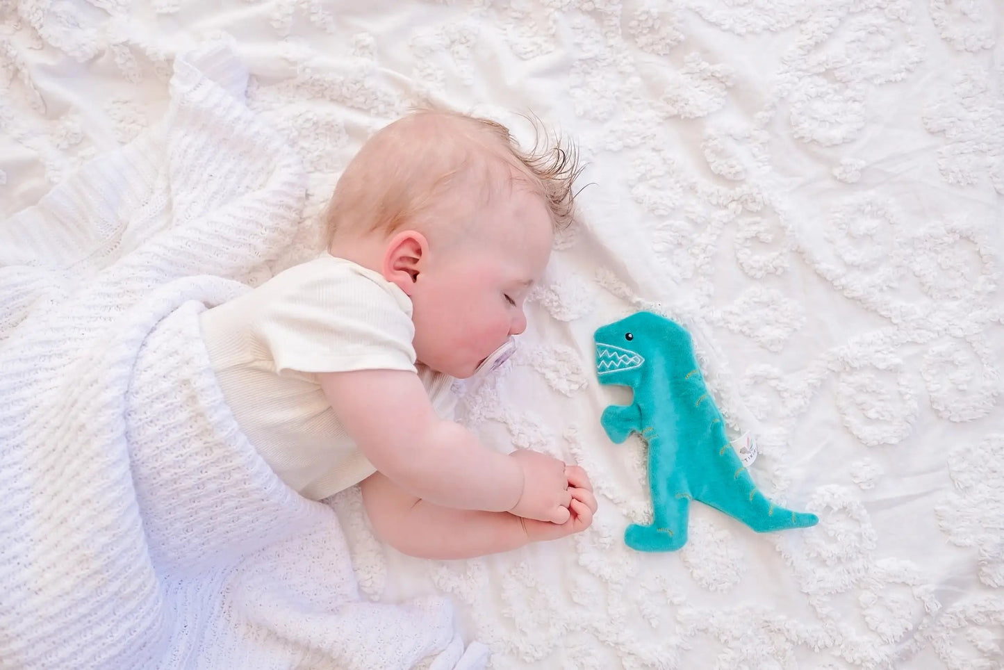 Baby sleeping next to cotton crinkle toy T-Rex