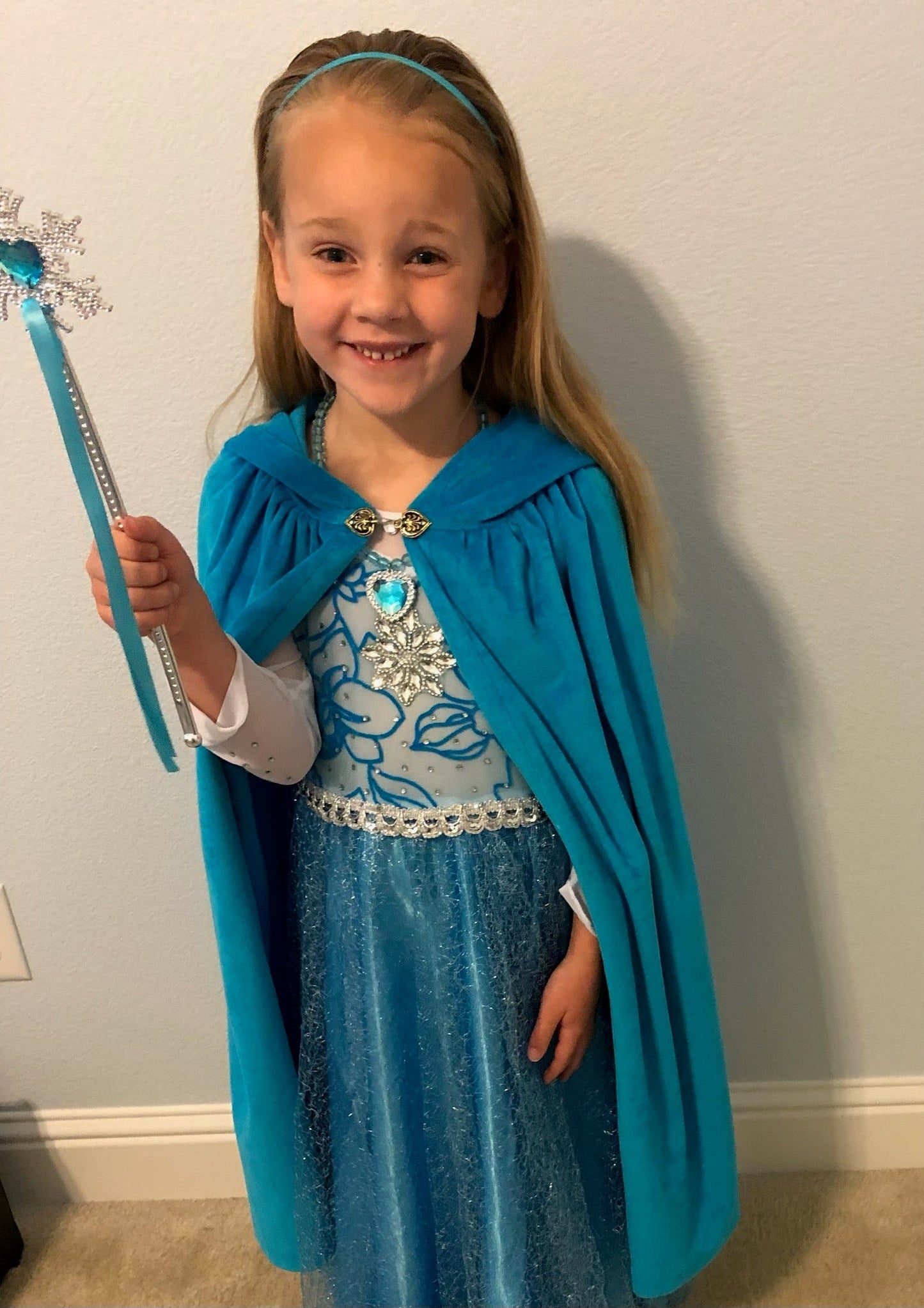 Child wearing blue hooded dress-up cape for imaginative play and costume use