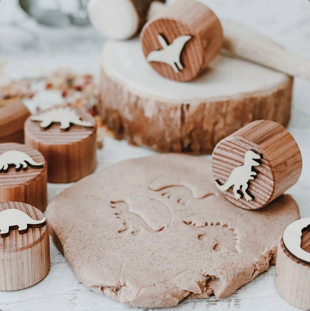 Dinosaur wooden dough stamps making fossil-style impressions in natural play dough