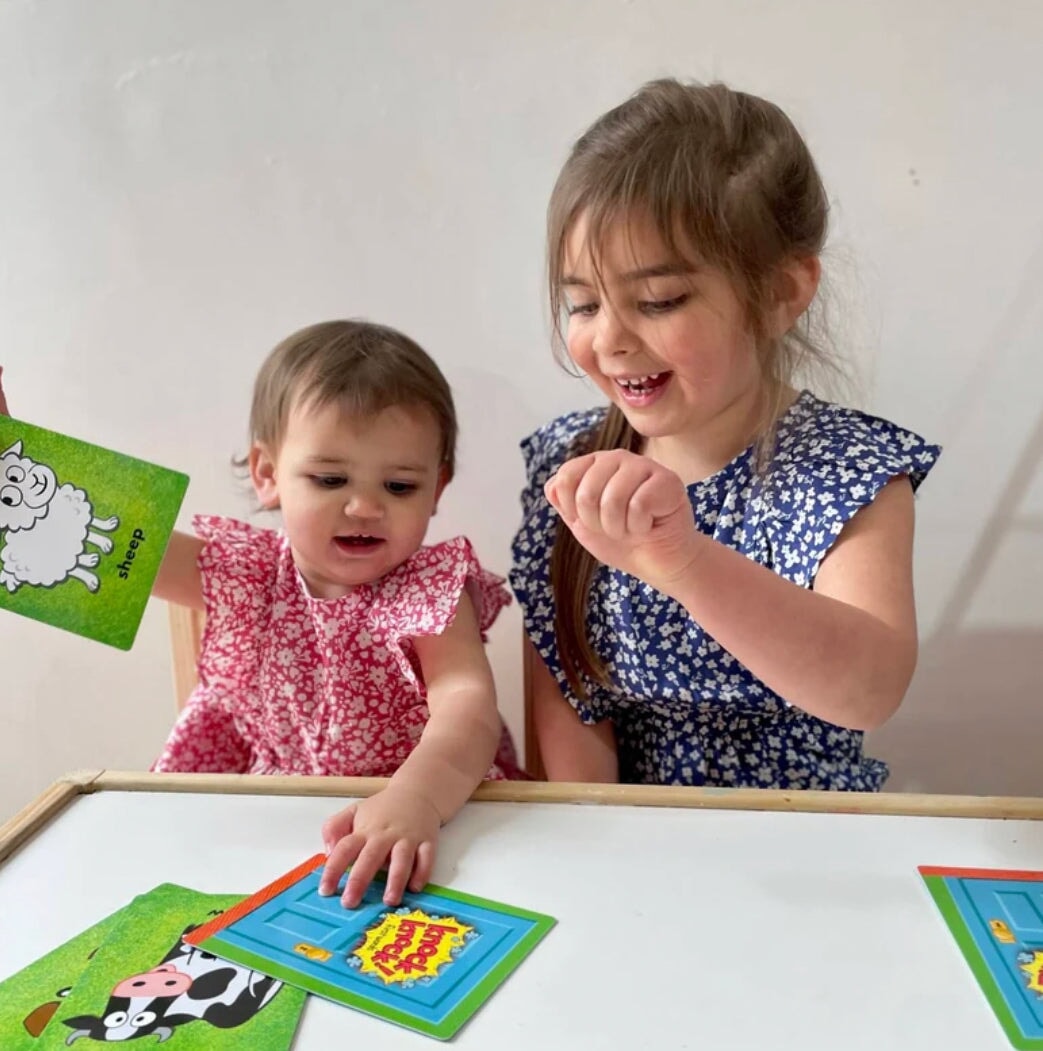A Preschooler and Toddler playing Knock Knock card game on a white table