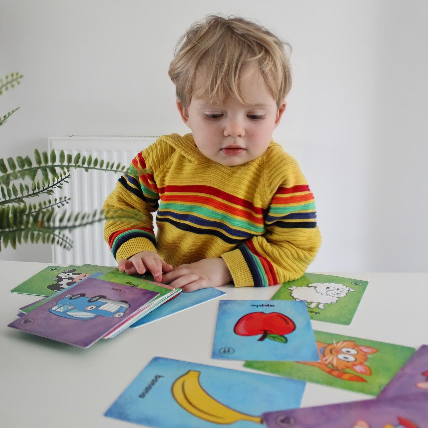A Toddler playing Knock Knock card game on a white table