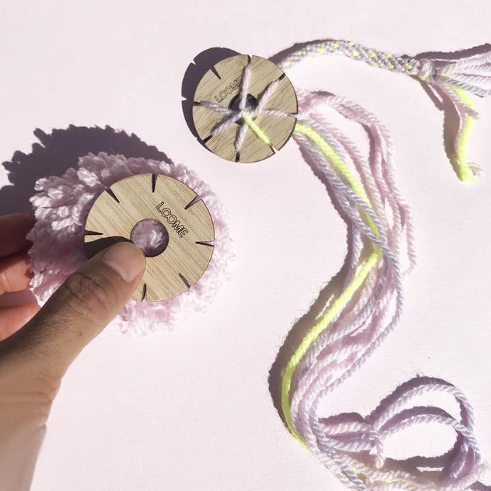 hand using Loome kumihimo maker to braid colorful cords for bracelets and fiber crafts