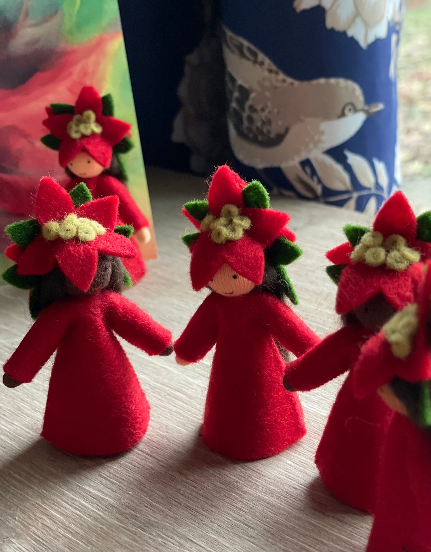 Four Poinsettia Flower Fairy Dolls -standing in front a window
