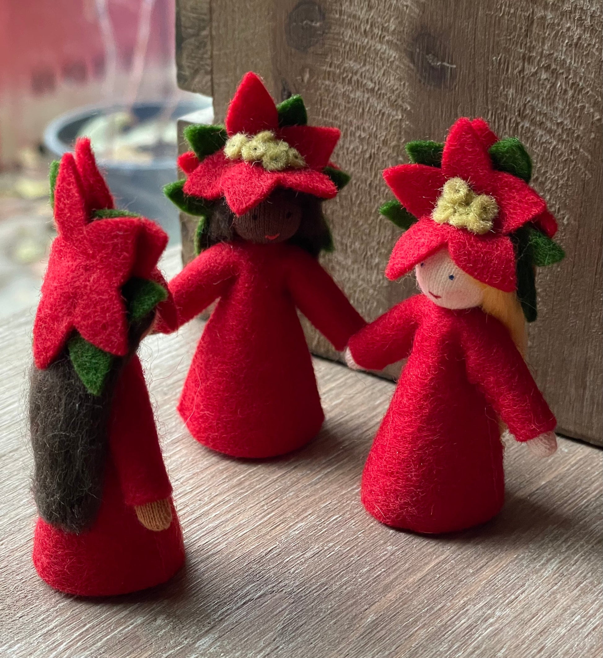 Poinsettia Flower Fairy Dolls in a semi-circle on a wooden table