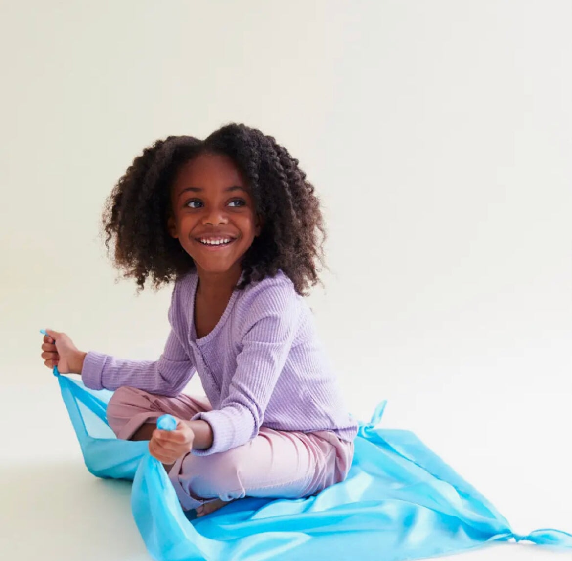 Girl sitting on sky blue playsilk smiling