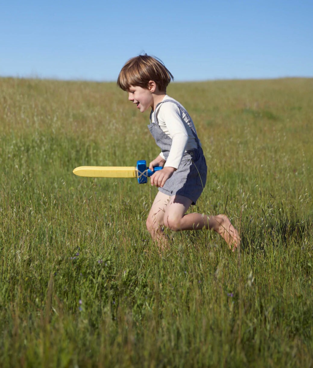 Child in a Grassy Meadow playing with a Soft Sword - Silk + Foam