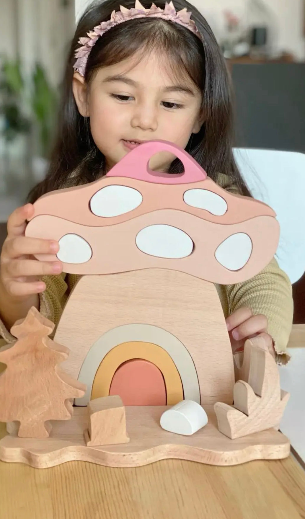 Child playing with a wooden toy mushroom with a rainbow arch for small world play
