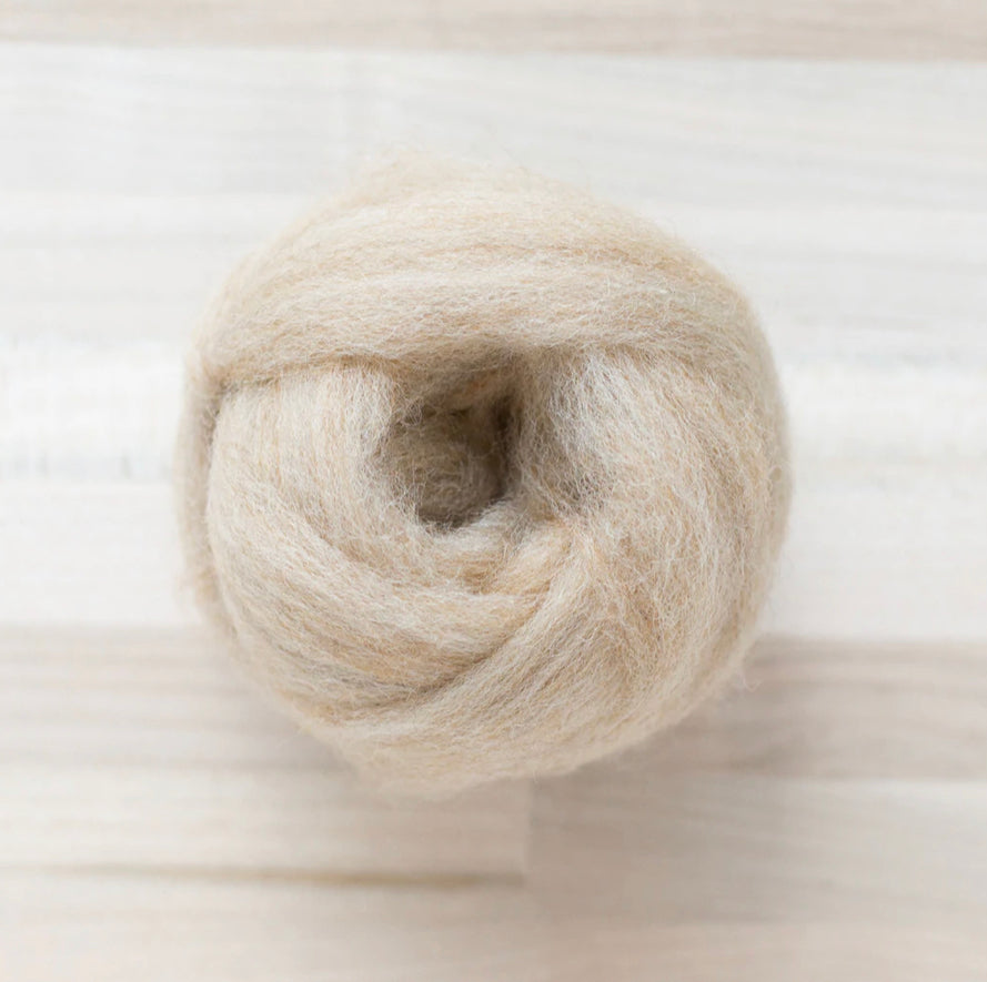 knot of wool roving in dune beige for needle felting on wooden background