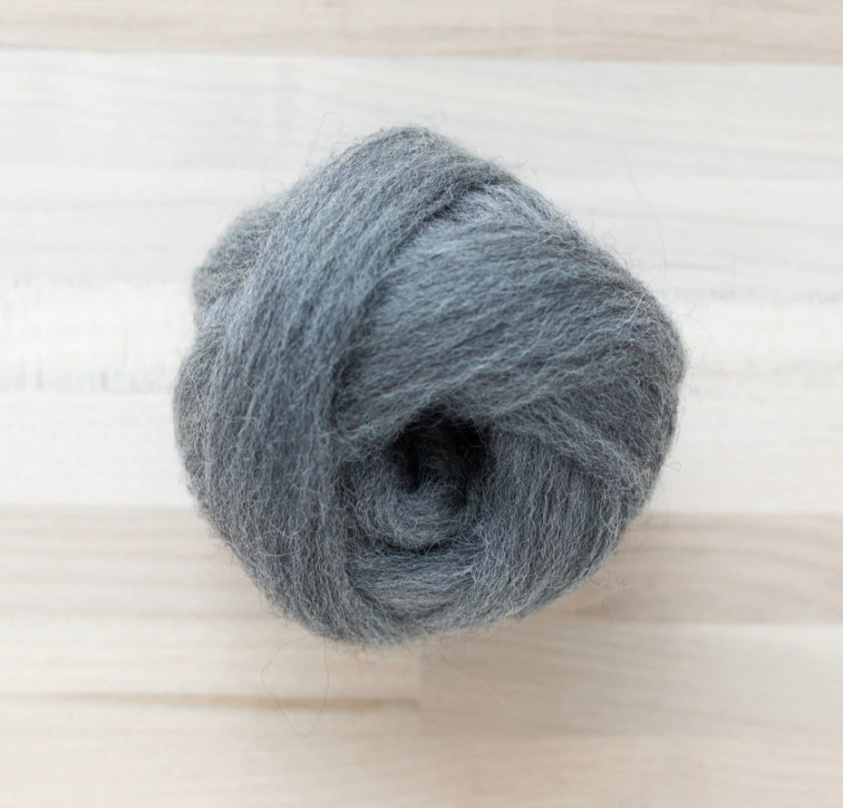 a knot of graphite grey wool roving for needle felting on wooden background