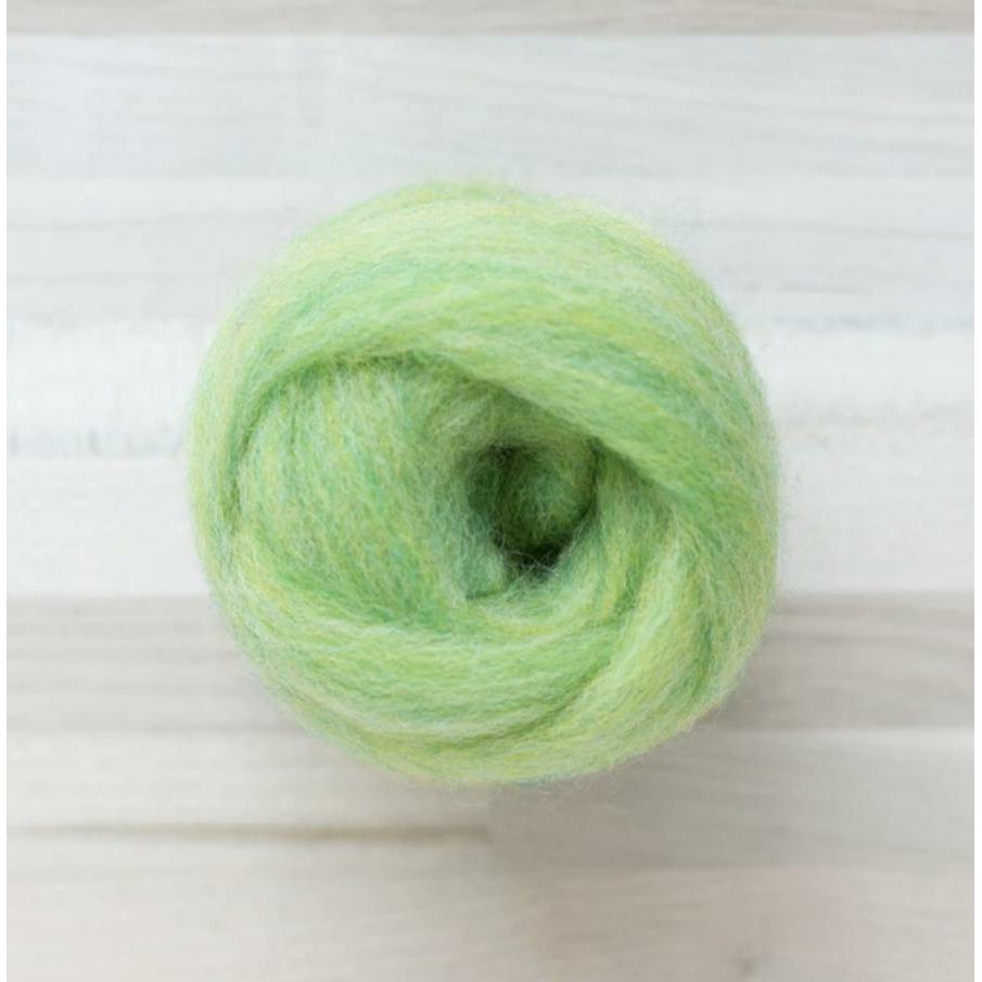 knot of wool roving in kiwi yellow green for needle felting on wooden background