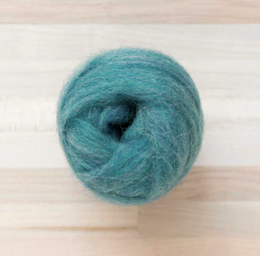 knot of wool roving in teal waters blue green for needle felting on wooden background